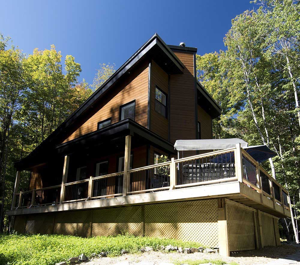 House plan exterior of a two-story modern home with wood siding, covered porch, and wraparound deck.