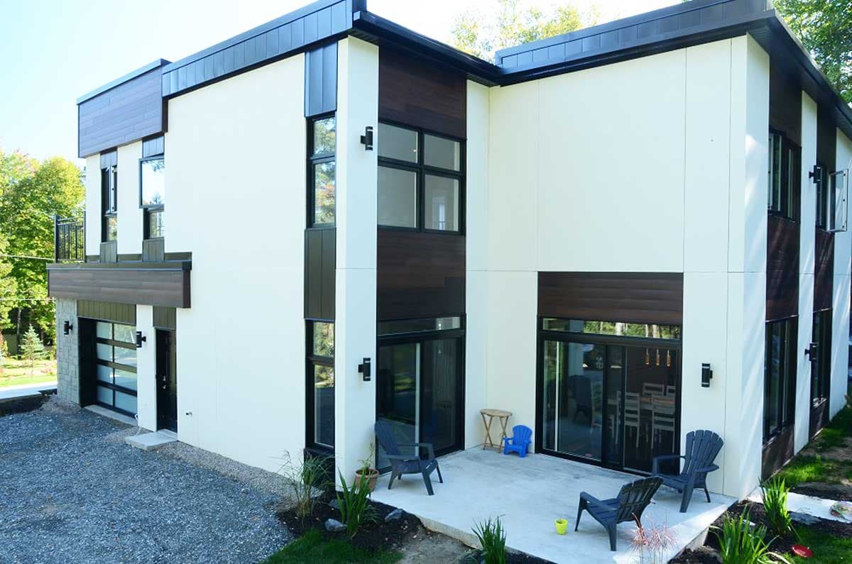 Modern two-story house plan exterior with white siding, dark wood accents, balcony, and glass garage door.