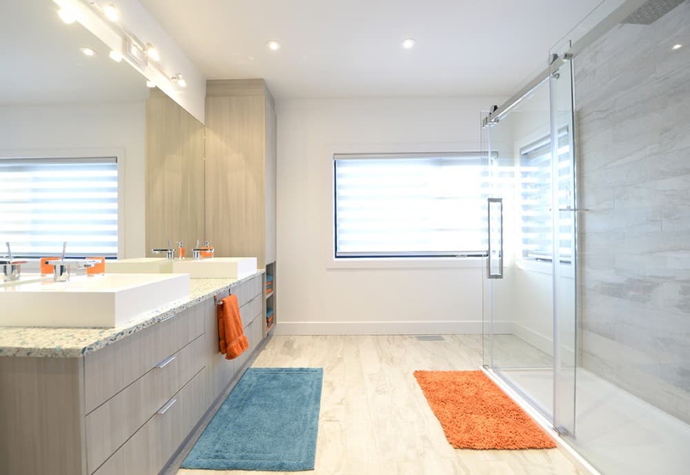 Modern bathroom with double vanity, wall-mounted cabinetry, and glass-enclosed shower with marble tile.