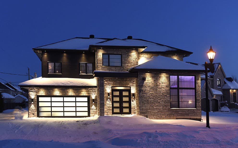 Two-story house plan exterior with stone facade, modern garage door, and glass-paneled front door.