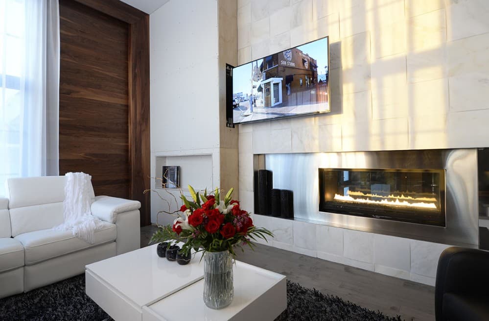 Living room with white sectional sofa, linear gas fireplace, flat-screen TV, and wood accent wall.