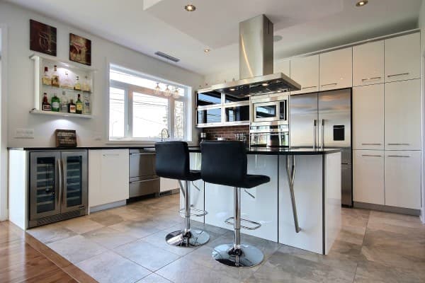 Modern kitchen with island seating, stainless steel appliances, wine fridge, and bar area.