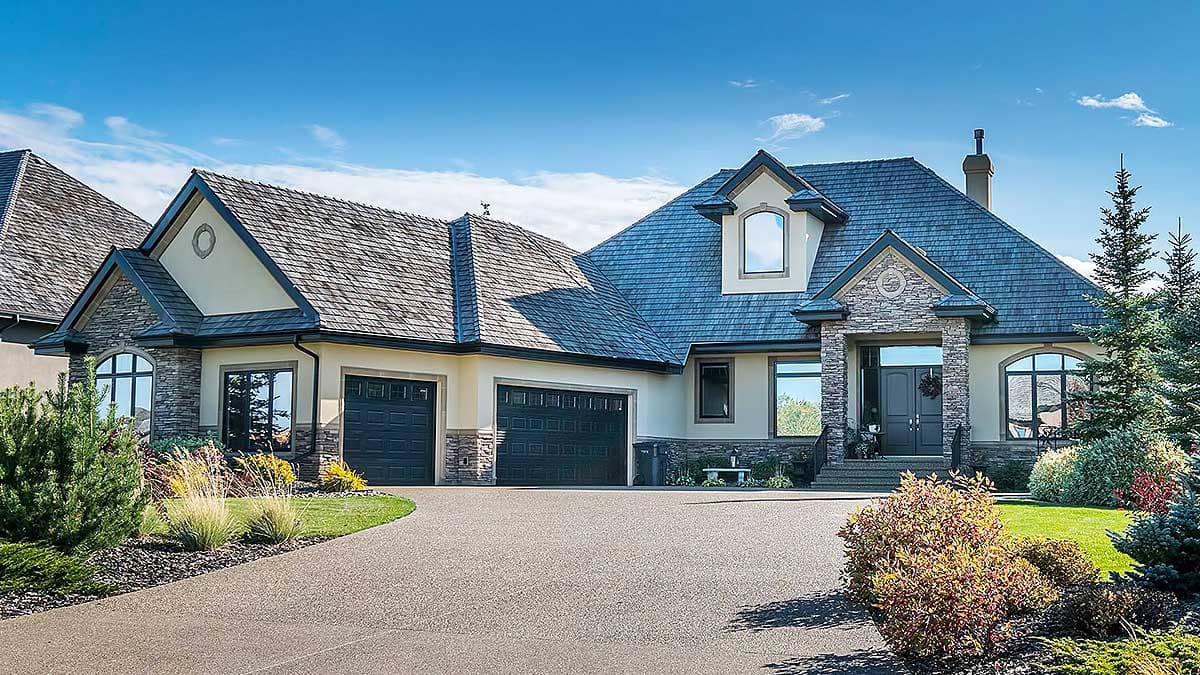 House plan exterior: two-story dwelling with a three-car garage, gabled rooflines, stone accents, and dormer windows.