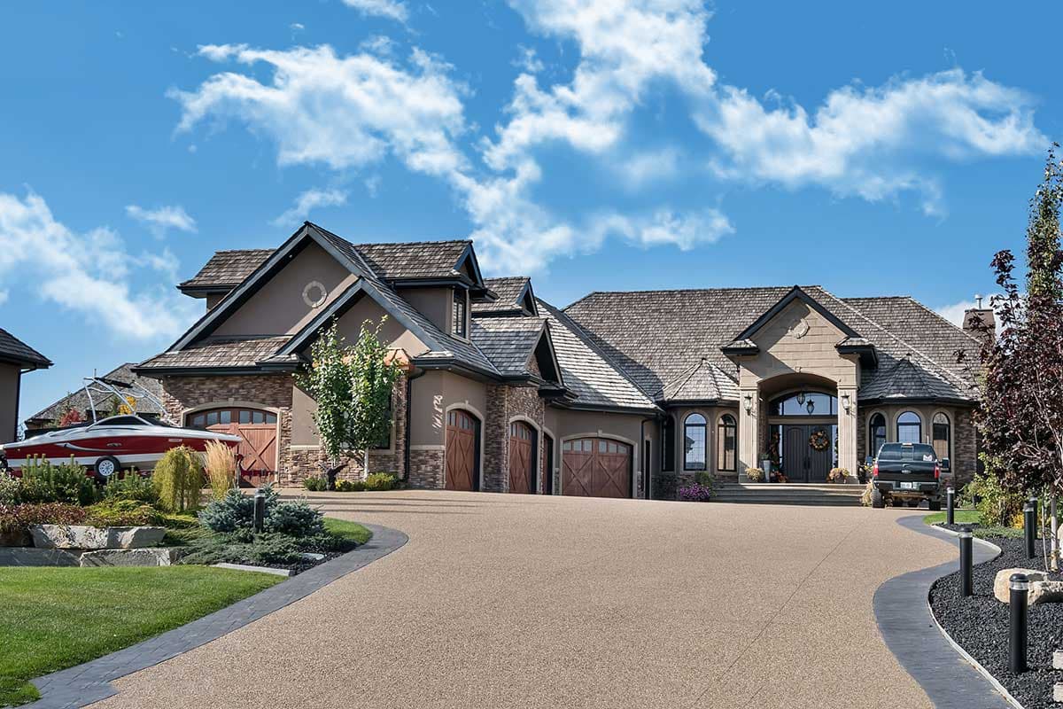 House plan exterior: multi-story home with layered rooflines, stone accents, arched garage doors, and a covered entryway.