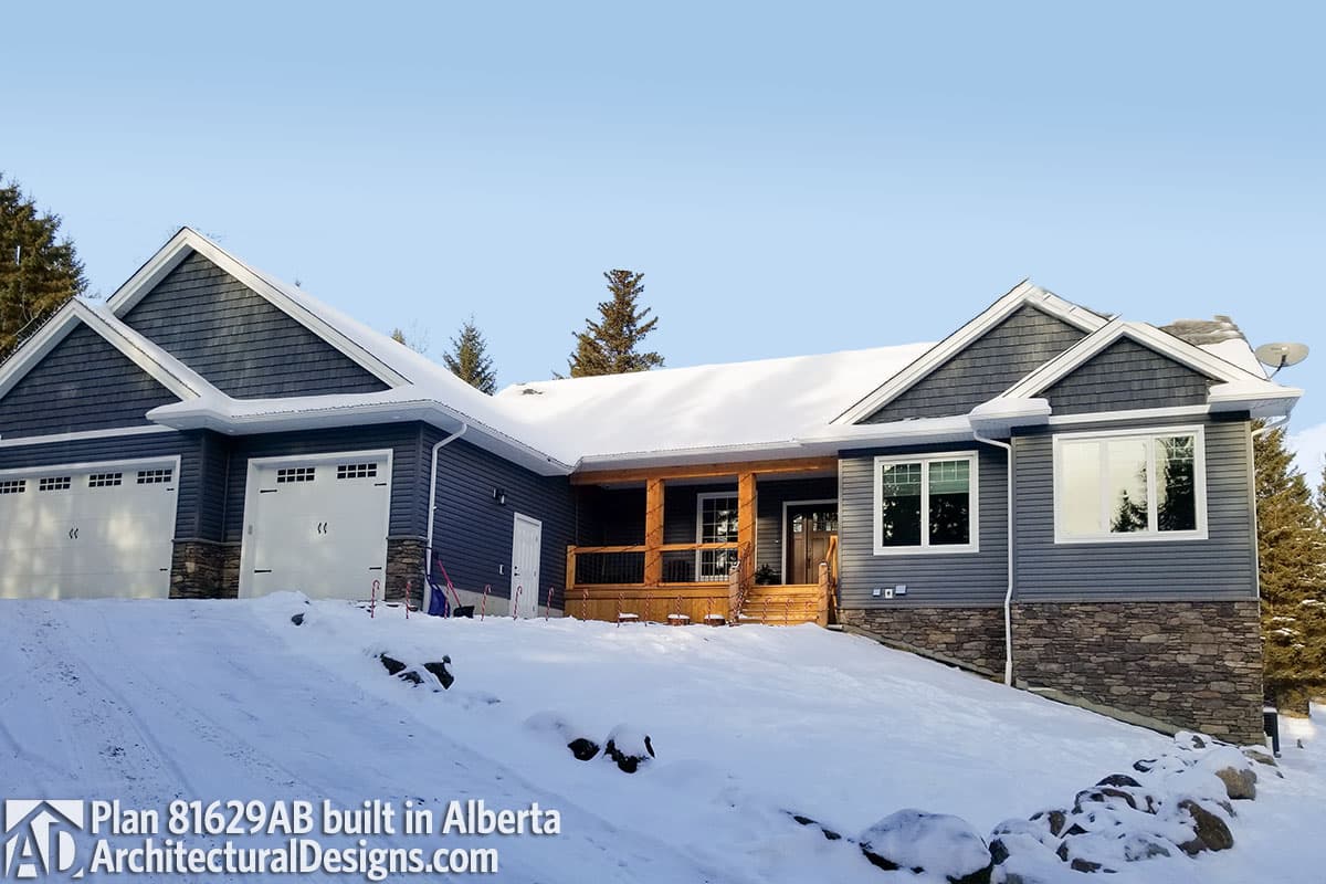 House plan exterior: Modern Ranch with three-car garage, gabled dormers, covered entry porch with wooden posts, and stone foundation accents.