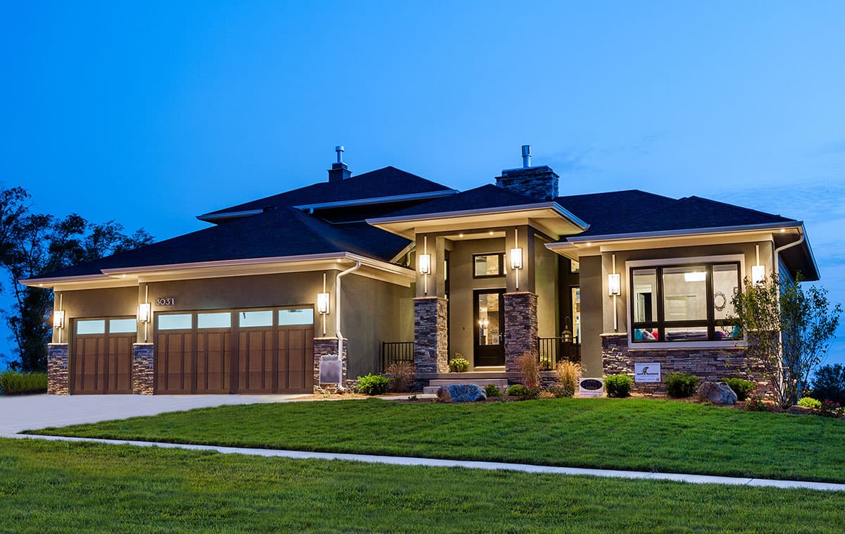 House plan exterior. Modern style, single story home with attached garage, stone accents on exterior columns, and flat rooflines.