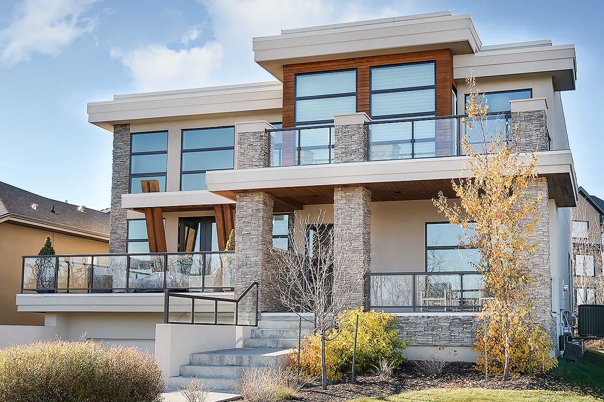 Modern two-story house plan exterior with stone pillars, large windows, balconies, and wood accents.