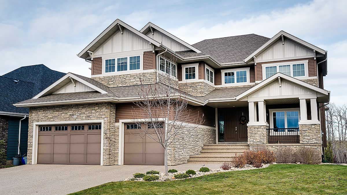 House plan exterior. Two-story home with stone and siding facade. Features include multiple gables, a covered porch, and a two-car garage.