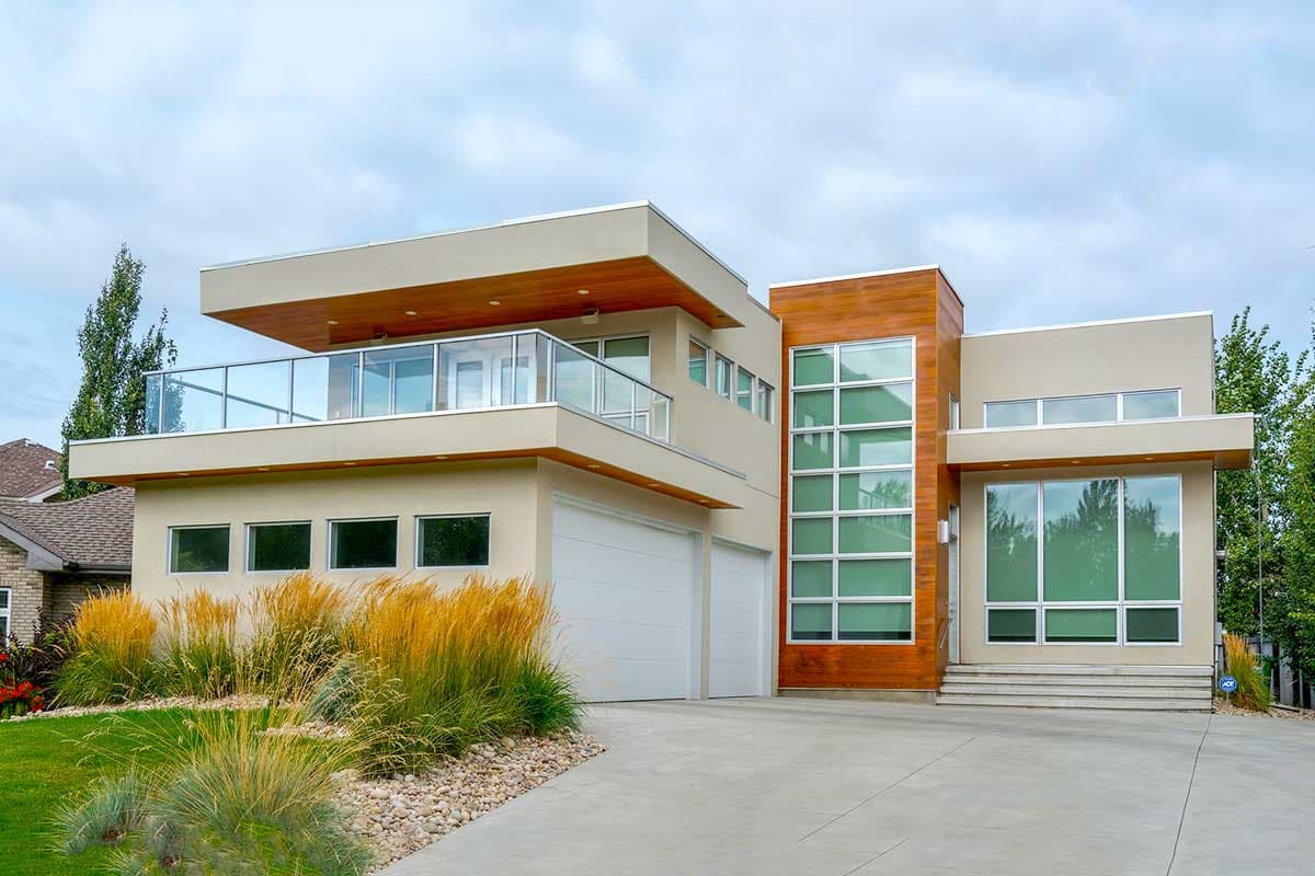 Modern house plan exterior with two-car garage, cantilevered second story, glass balcony railing, and wood accents.