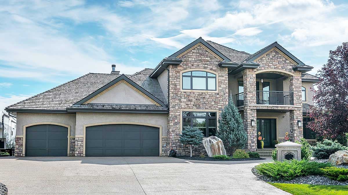 House plan exterior: Two-story home with stacked stone accents, a covered balcony, and a three-car garage.
