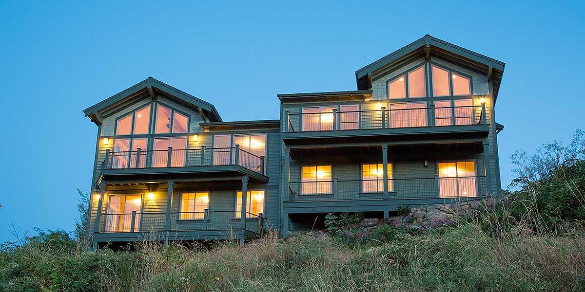 Exterior house plan with multiple levels, large gable windows, balconies, and horizontal siding.