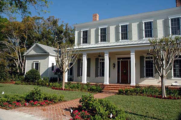 House plan exterior: Two-story Traditional style home with a wraparound porch, gabled dormers, and brick walkway.