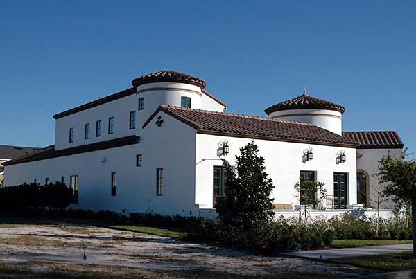 Spanish-style house plan exterior with two stories, white stucco walls, tile roof, and prominent rounded towers.