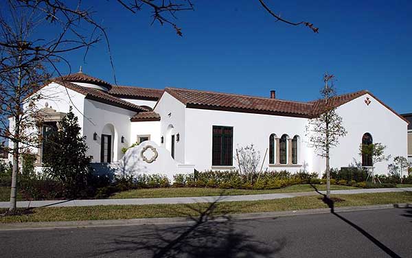 Spanish-style house plan exterior with white stucco, tile roof, arched windows, and a prominent turret.