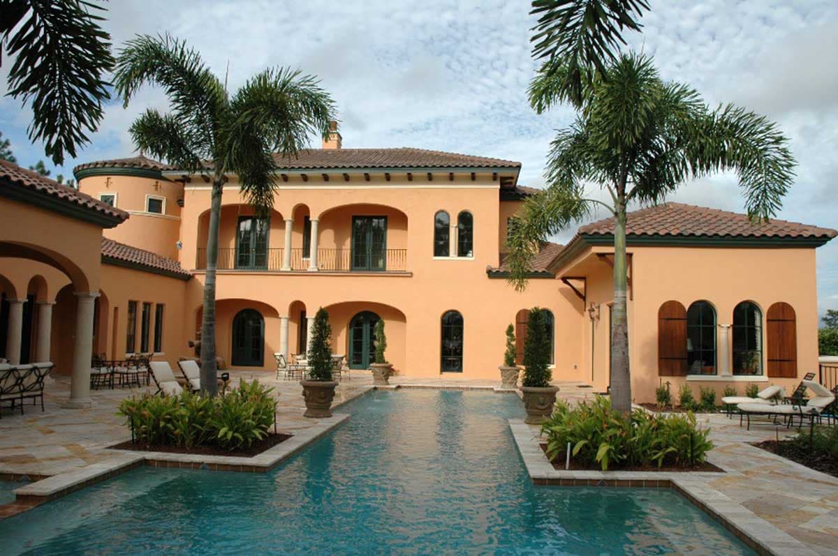 House plan exterior features a multi-story Italianate style residence with arched windows, a covered balcony, and a courtyard pool.