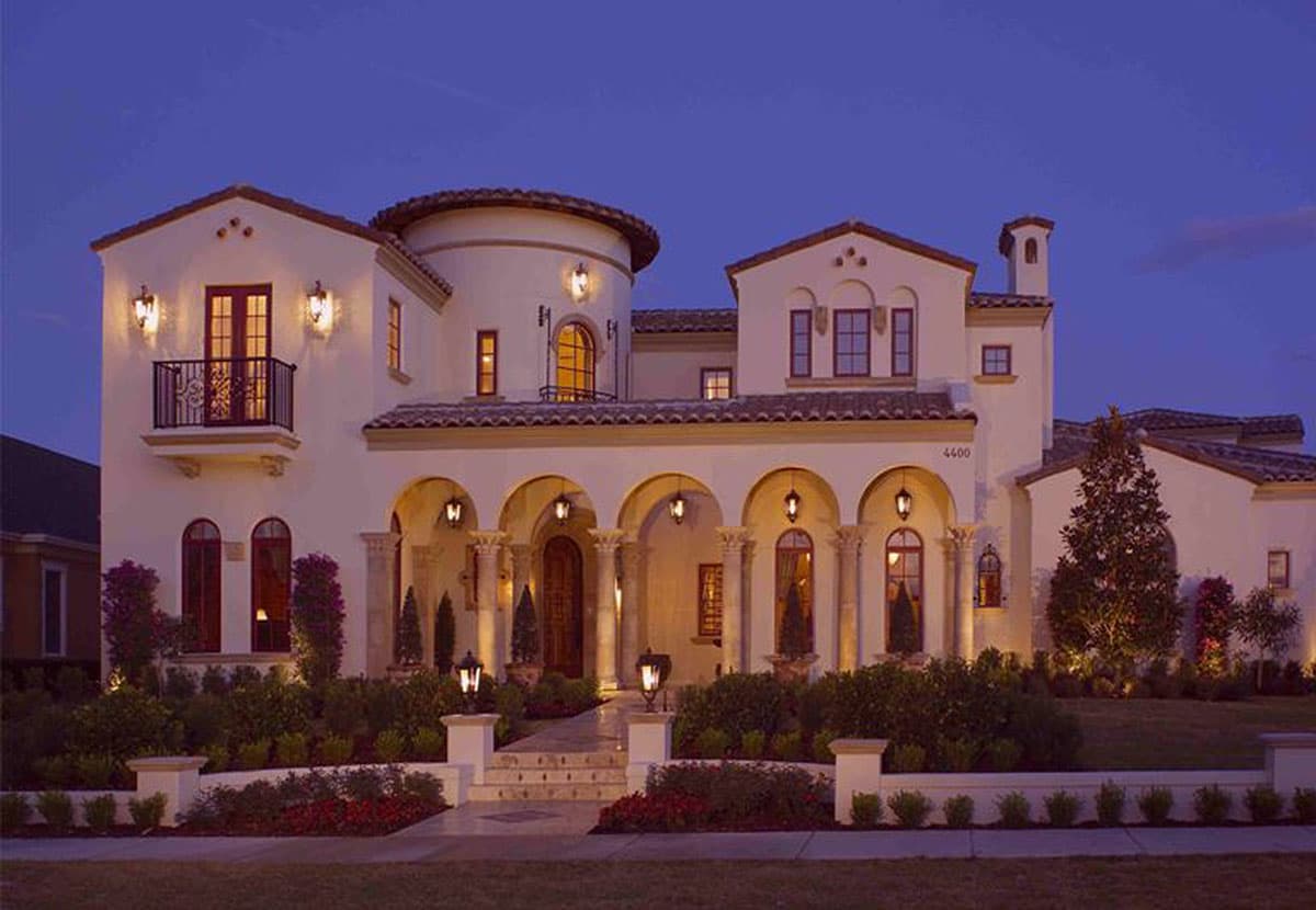 House plan exterior: Mediterranean style, two stories, arched loggia entrance, rounded tower element, and wrought iron balcony.