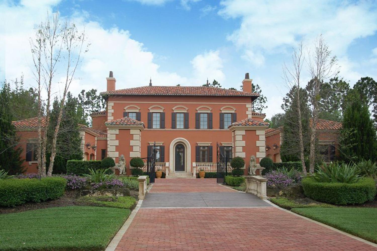 Italianate house plan exterior, two stories, stucco finish, arched entryway, double chimneys, and tiled roof.