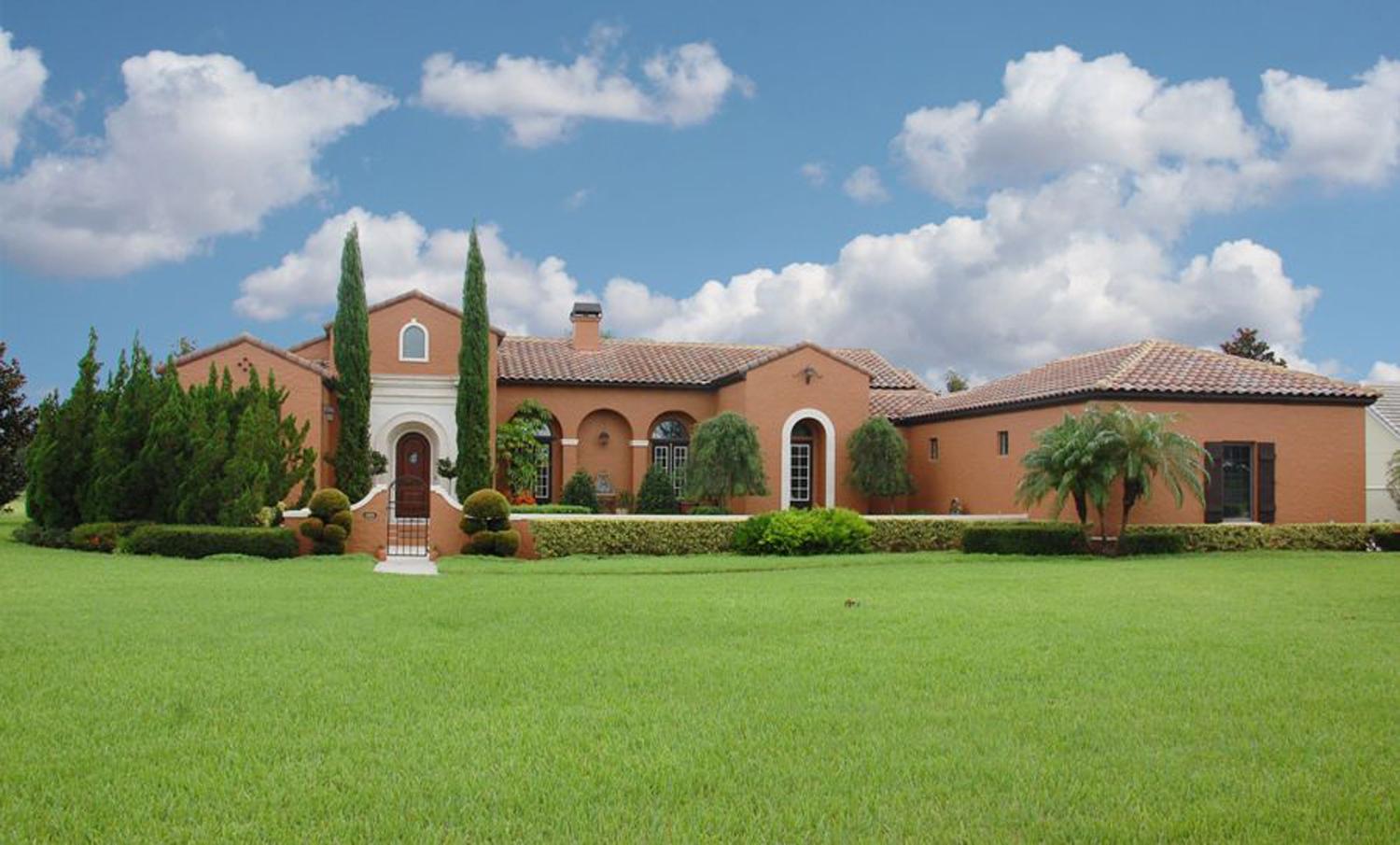 Mediterranean style house plan exterior with a clay tile roof, arched windows, and a prominent entryway with columns.