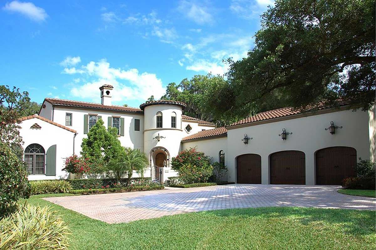 House plan exterior: Mediterranean style, two stories, arched windows, round turret, and three-car garage.