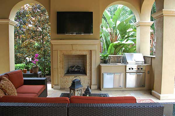 Outdoor living space with fireplace, television, and built-in grill station.