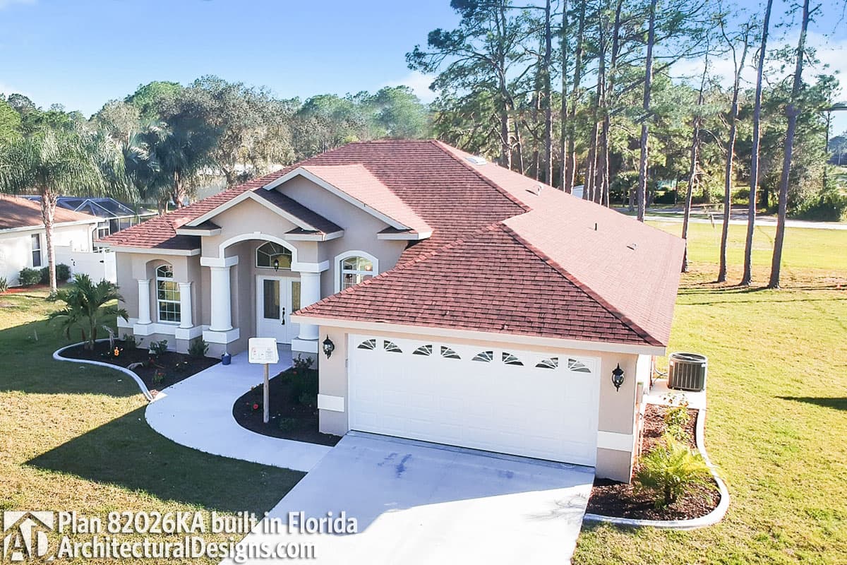 House plan exterior: One-story Ranch home with covered entry, arched windows, and a two-car garage.