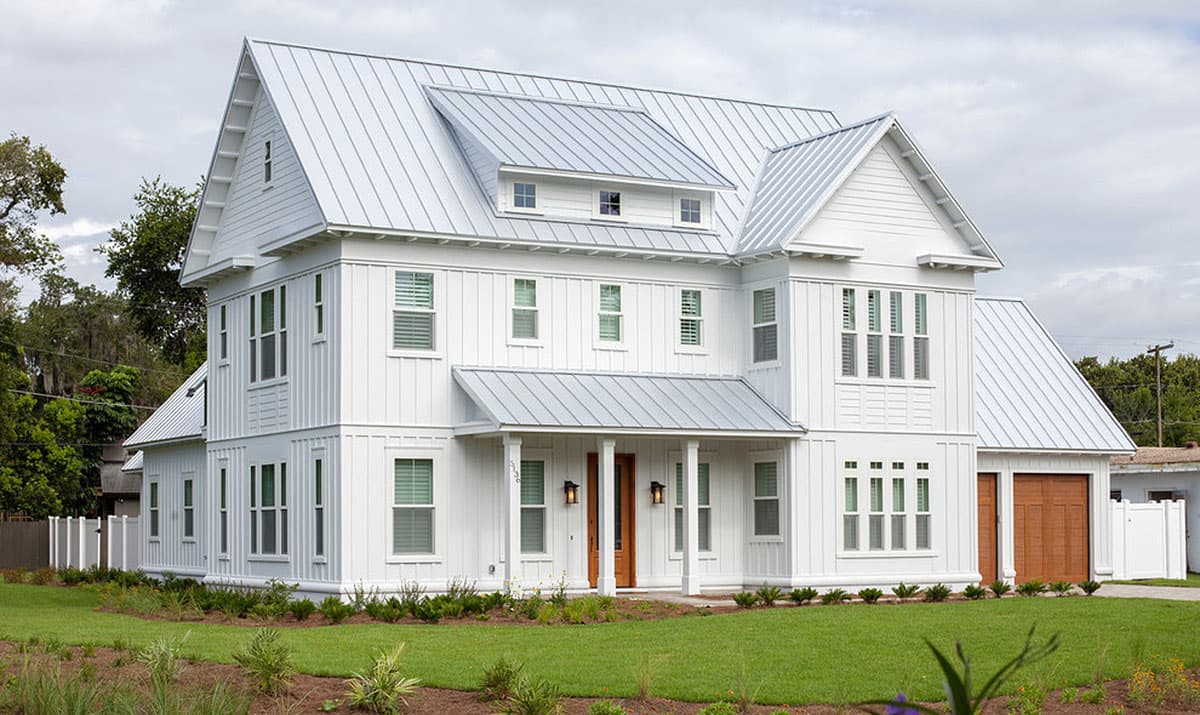 House plan exterior featuring a two-story farmhouse style with metal roofing, multiple gables, and a front porch. Garage visible on the right.