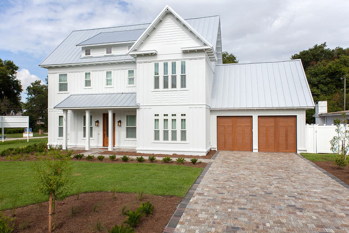 House plan exterior: Modern Farmhouse style, two-story with metal roof, covered porch, and a three-car garage.