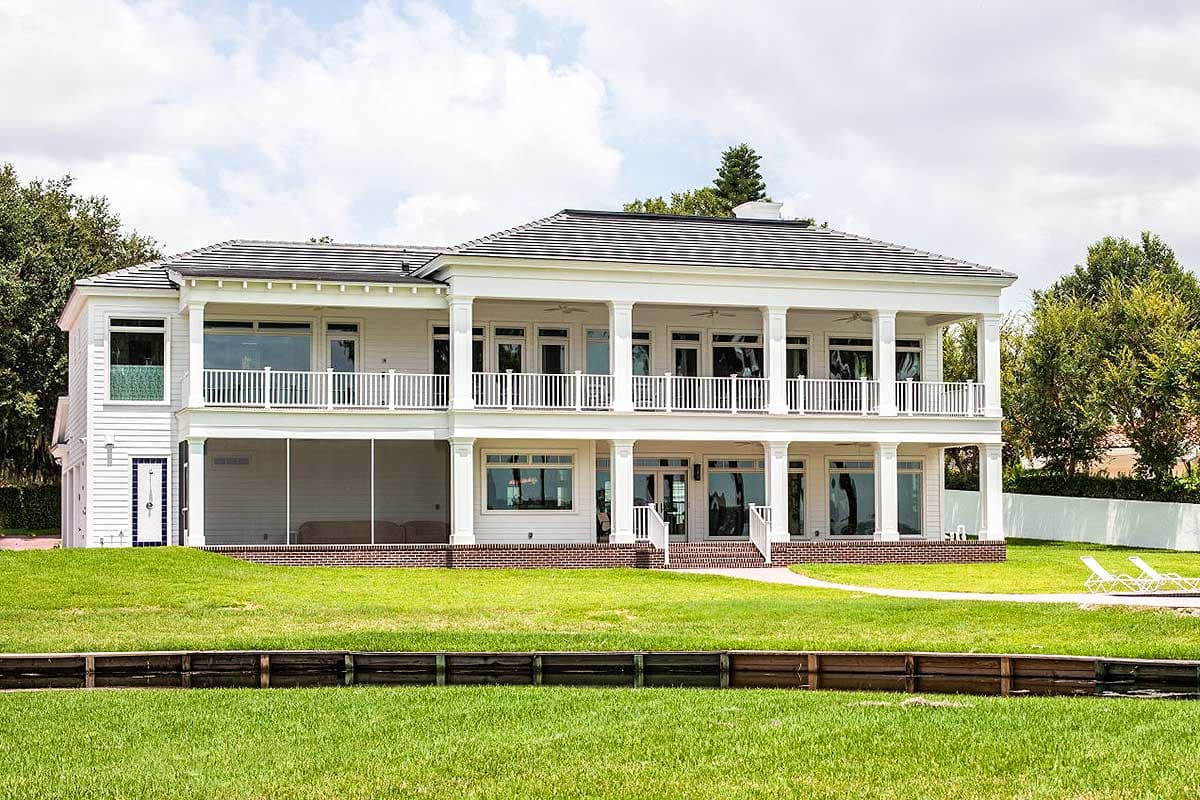 Two-story house plan exterior with a full-width second-story balcony supported by columns and a screened porch on the first level.