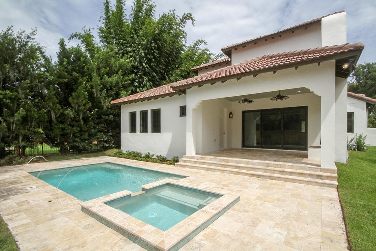 House plan exterior with Spanish tile roof, covered patio, and swimming pool. Features stucco walls and dark-framed windows.