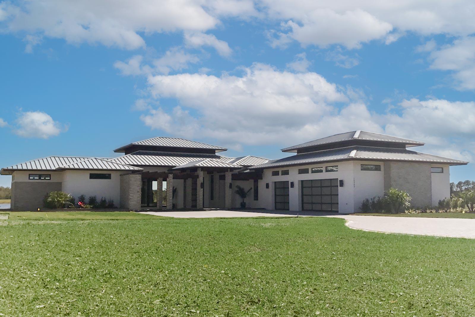 House plan exterior with modern design. Features include flat metal roofs, a covered porch, and a two-car garage. Stone and stucco exterior.