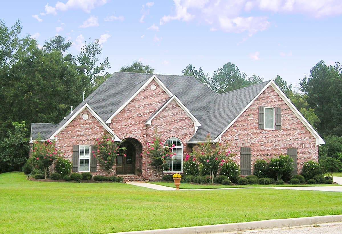 House plan exterior: One-story brick home with arched entryway, multiple gables, dormer window, and shutters.