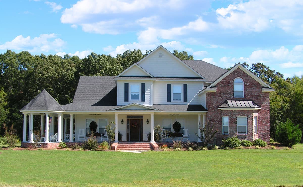 House plan exterior: Two-story home with full-width porch, wraparound gazebo, dormer, and brick accents.
