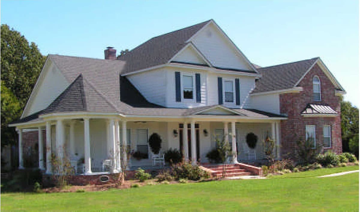 House plan exterior: two-story, white siding with red brick accents, wraparound porch, multiple gables, and a dormer.
