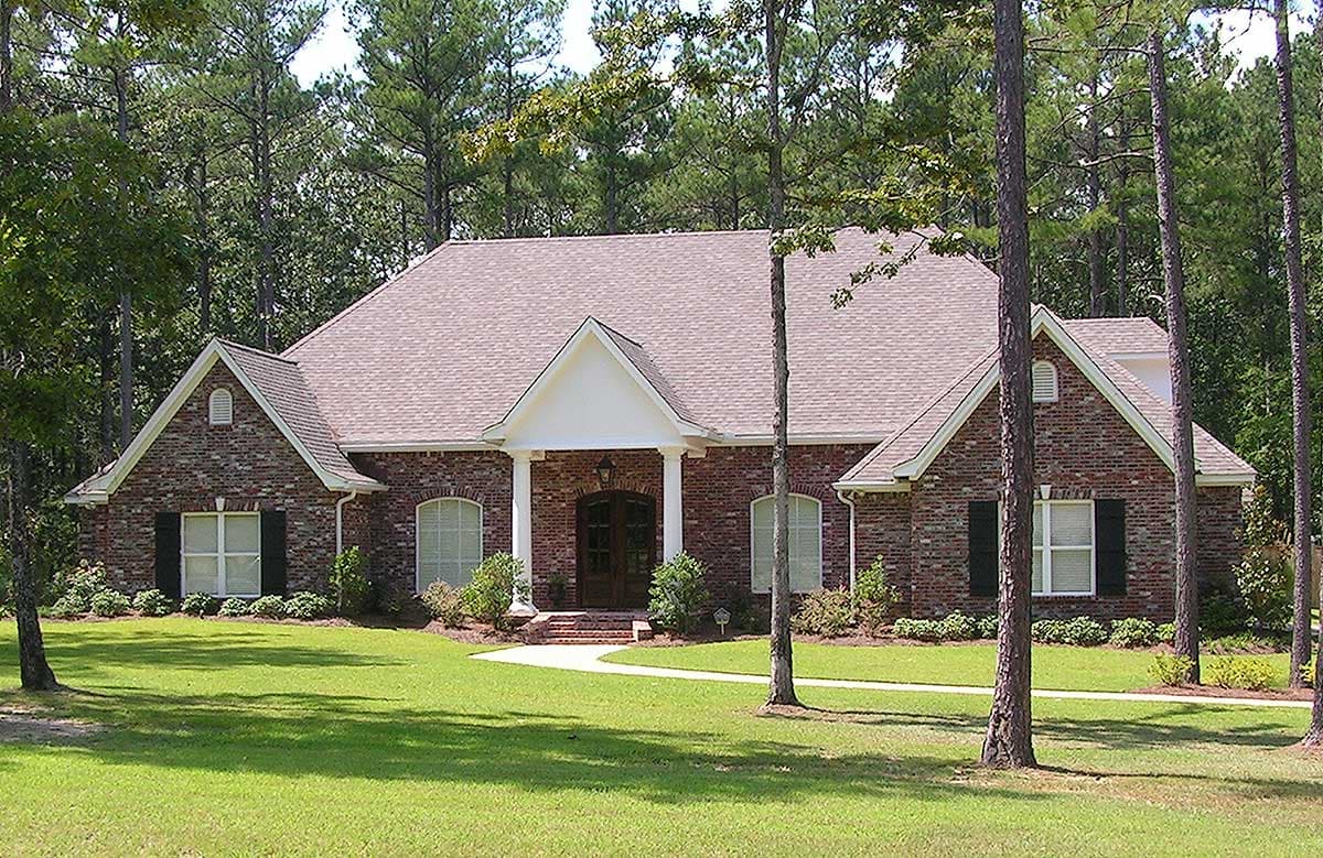 House plan exterior: One-story brick home with a covered entry, arched windows, gables, and a multi-pitched roof.
