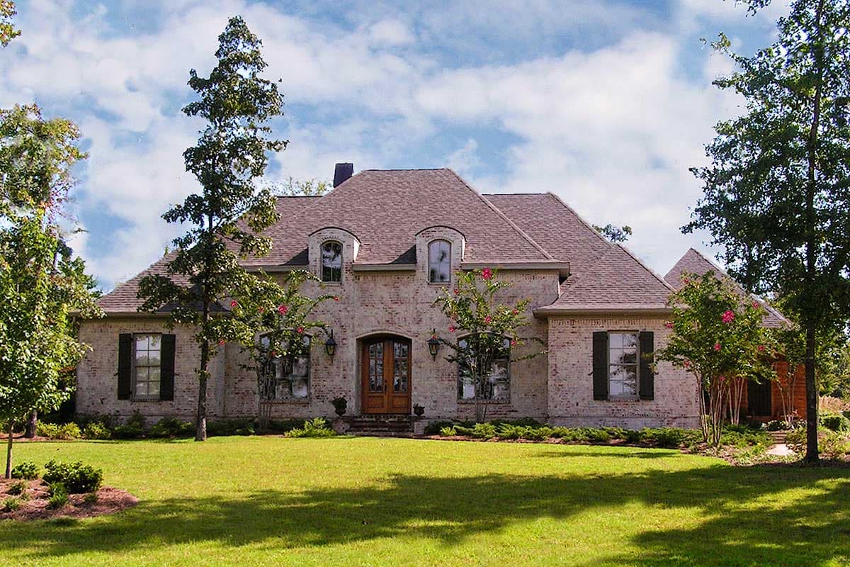 House plan exterior of a two-story brick home with arched dormers, a prominent roofline, and double entry doors.