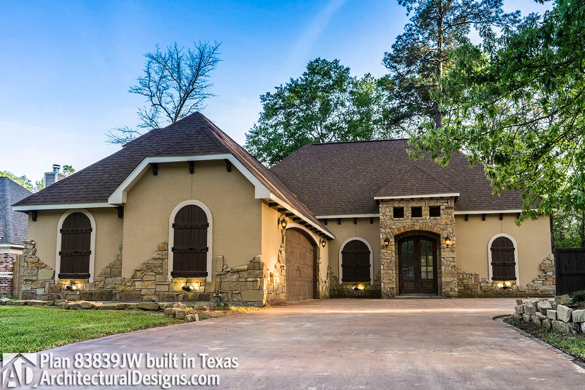 House plan exterior with arched windows, stone accents, and a two-car garage.