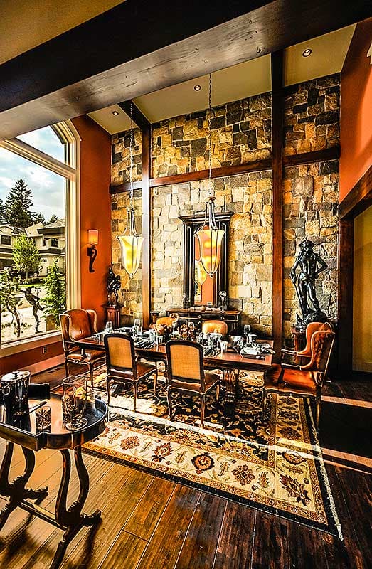 Dining room with stone accent wall, chandelier, large window, and a rug.