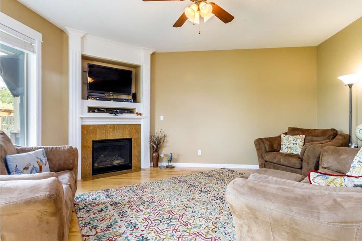 Living room with fireplace, television alcove, large windows, and seating area.