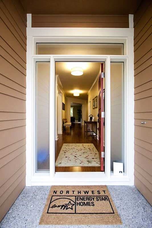 View into house from entrance, showing a carpeted hallway with two ceiling lights and furniture.
