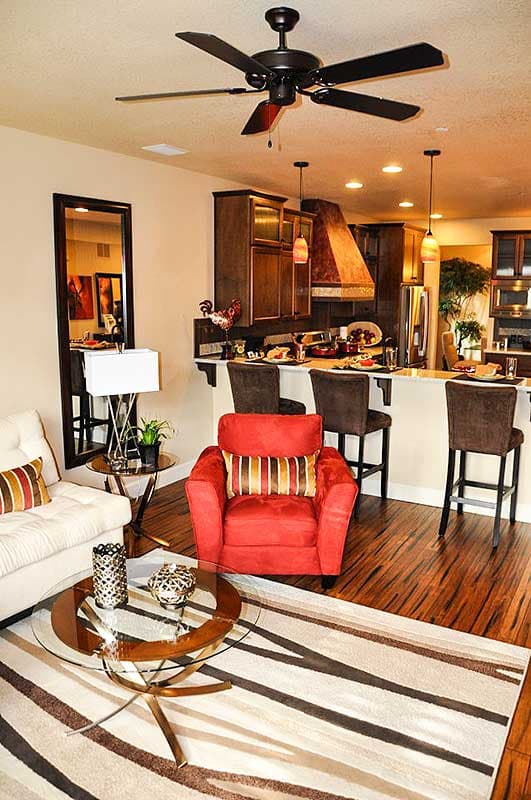 Open concept living area and kitchen with island seating, dark wood cabinets, and a ceiling fan.