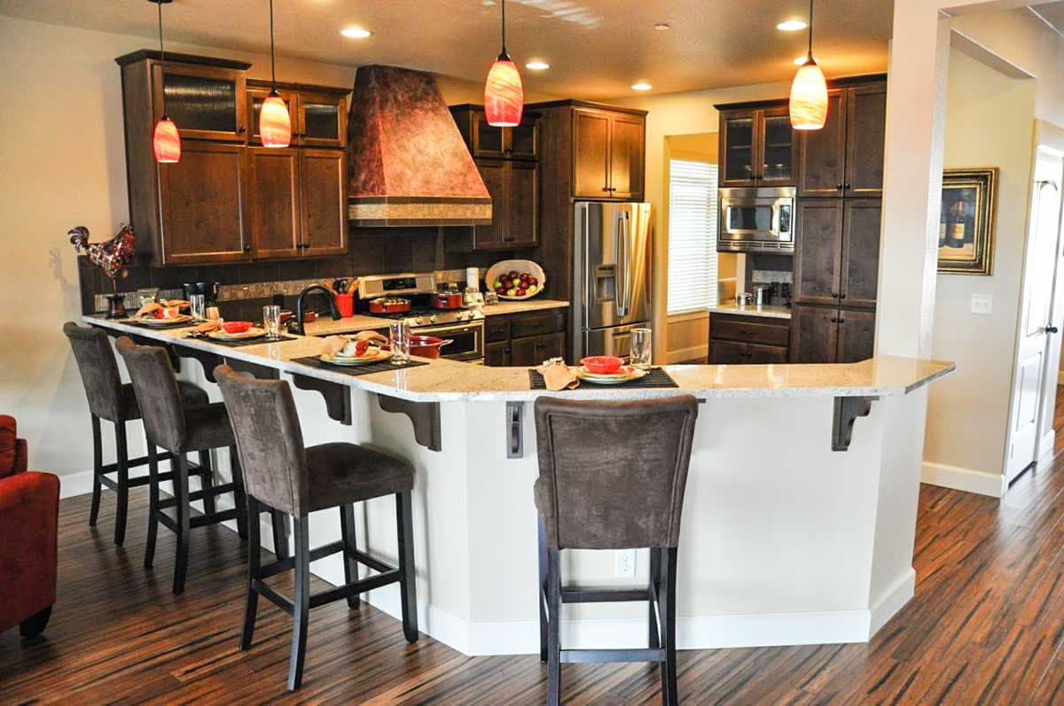 Kitchen featuring dark wood cabinets, granite-look counter, breakfast bar with seating, and stainless steel appliances.