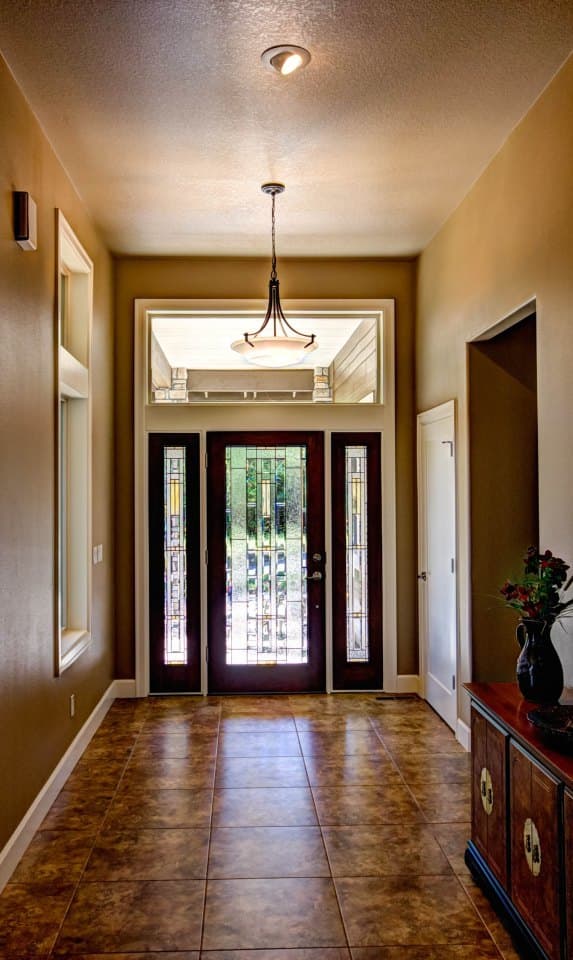 Entryway interior view showing a glass-paneled double door, sidelights, tiled floor, and pendant lighting.