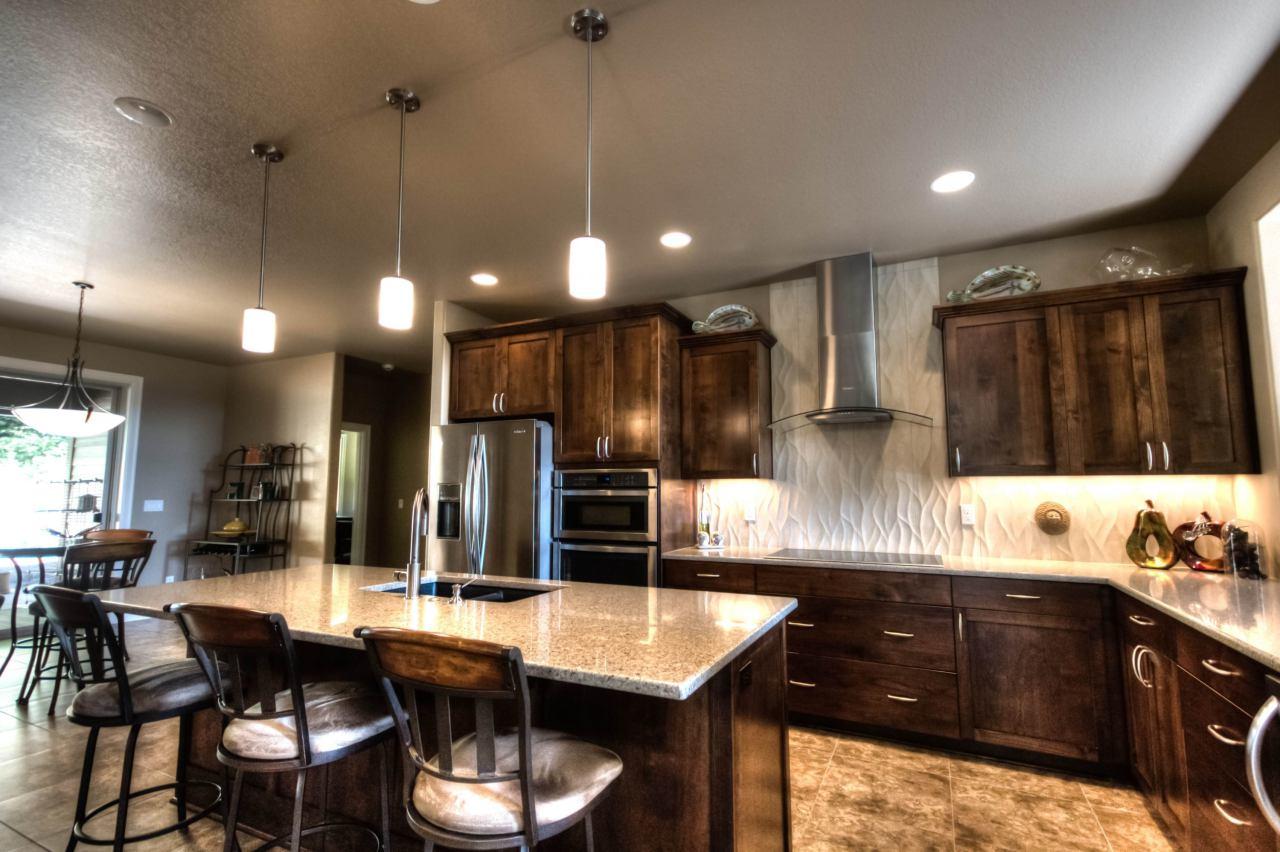Kitchen with island, granite countertops, dark wood cabinets, stainless steel appliances, and textured backsplash.