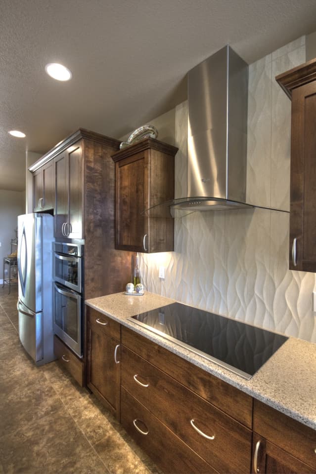 Kitchen with built-in oven, cooktop, stainless steel range hood, and custom wood cabinetry.