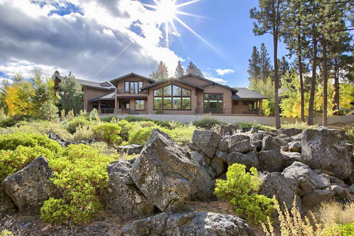 House plan exterior: Modern style, two stories, large window walls, covered deck, and multiple gables.