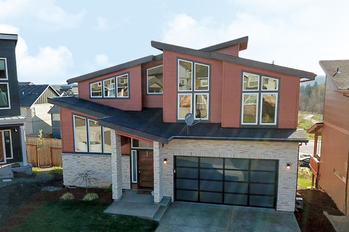 House plan exterior with modern design. Two-story home with a flat roof, prominent gables, and a glass-paneled garage door.