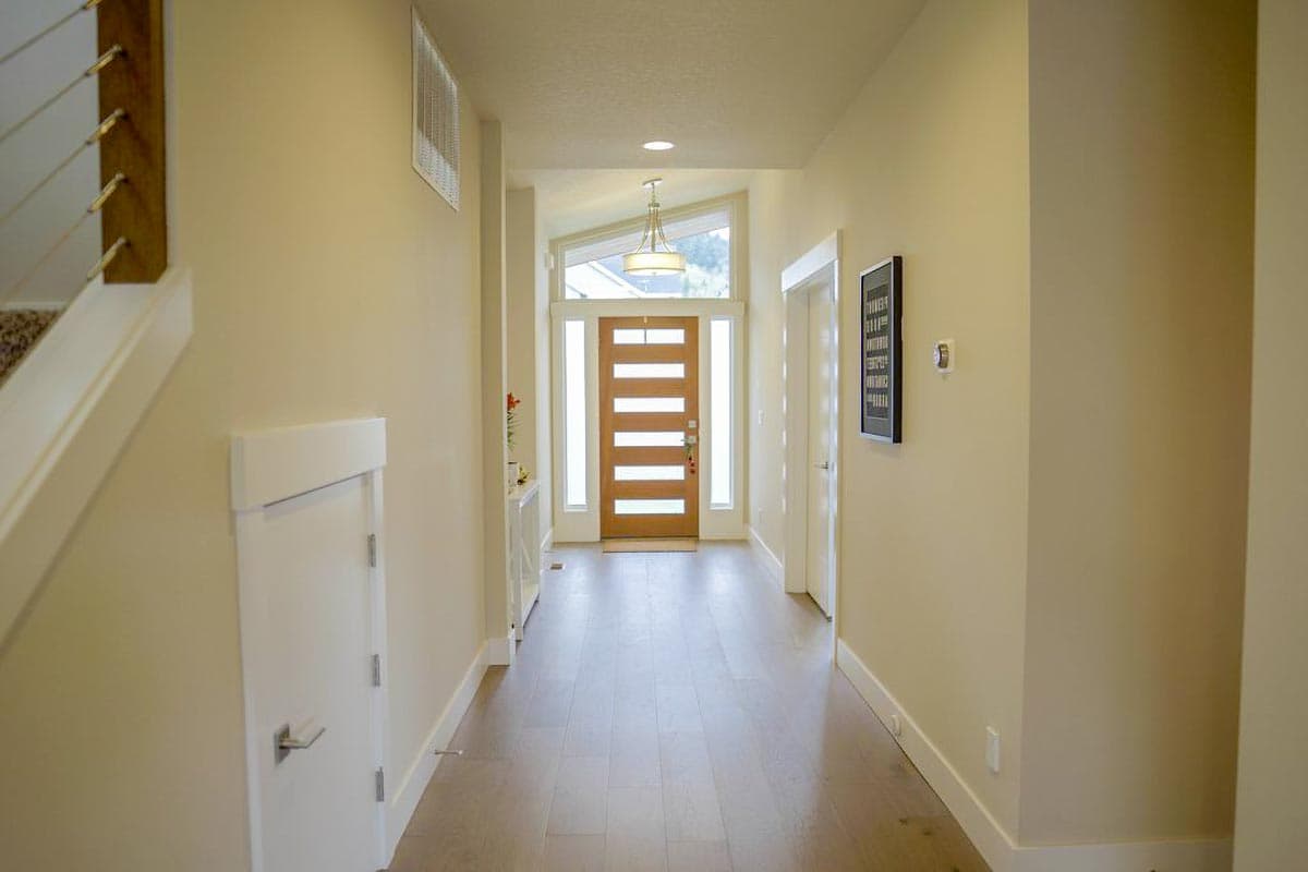 Modern entryway with glass panel door, transom window, and minimalist railing on staircase.
