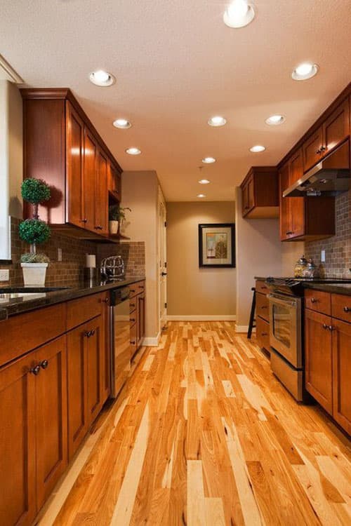Kitchen interior with cherry cabinets, granite countertops, tile backsplash, stainless steel appliances, and hardwood flooring.