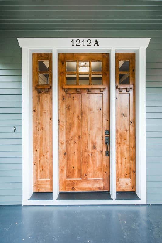 House plan exterior: Double wooden doors with glass transoms and flanking sidelight windows.