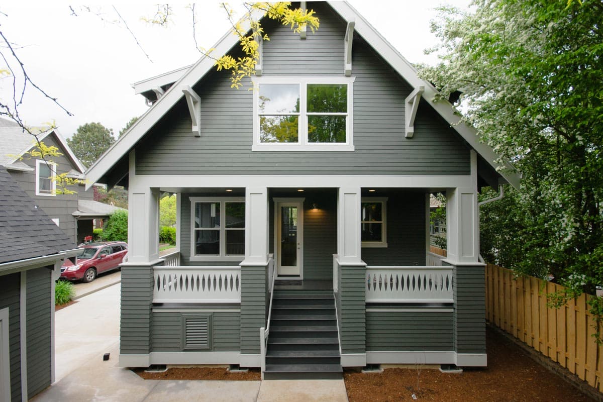 Craftsman style house plan exterior with full-width covered porch, decorative railing, and prominent gables with exposed rafter tails.